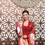Raline Shah berkebaya merah sambil memegang bendera Merah Putih.