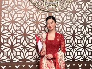 Raline Shah berkebaya merah sambil memegang bendera Merah Putih.