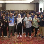 Peserta dan panitia kegiatan olahraga penyandang disabilitas berfoto bersama di dalam ruang pertemuan.