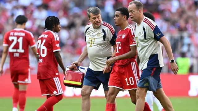 Jamal Musiala dipapah keluar lapangan oleh tim medis Bayern Munich.