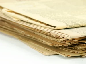 Tumpukan koran berusia seratus tahun dengan kertas menguning dan tepi yang sudah robek