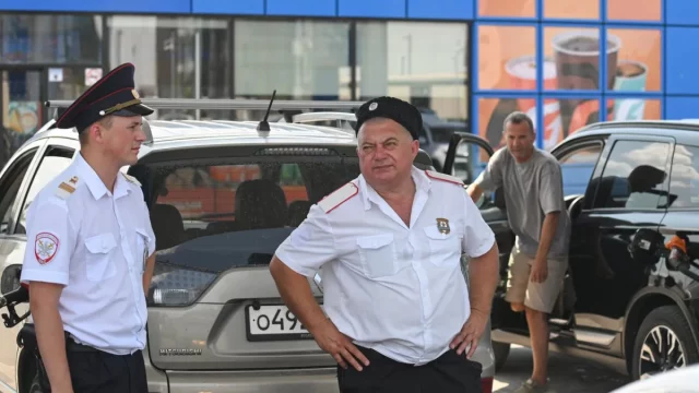 Petugas Cossack berjaga di antrean kendaraan pada sebuah stasiun pengisian bensin di Anapa, Rusia, saat kelangkaan bahan bakar.