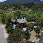 Ilustrasi kampung Minangkabau dengan rumah gadang dan petak sawah di lereng perbukitan.
