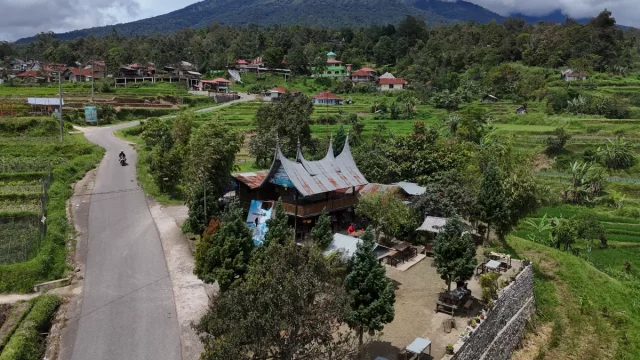Ilustrasi kampung Minangkabau dengan rumah gadang dan petak sawah di lereng perbukitan.