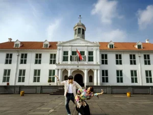 Gedung putih bekas balai kota Batavia dengan atap merah dan menara jam, dilihat dari Lapangan Fatahillah, Kota Tua Jakarta