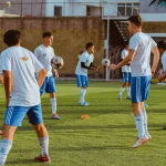 Ilustrasi sekelompok pemain sepak bola usia muda berlatih menggiring dan mengoper bola di lapangan rumput