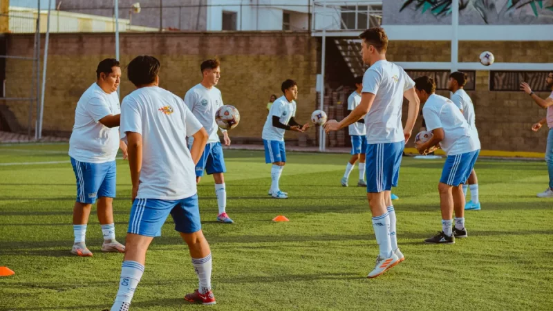 Ilustrasi sekelompok pemain sepak bola usia muda berlatih menggiring dan mengoper bola di lapangan rumput