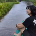 Leony duduk di atas perahu saat menyusuri sungai di Kalimantan.
