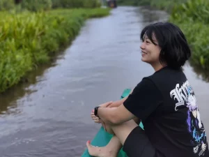 Leony duduk di atas perahu saat menyusuri sungai di Kalimantan.