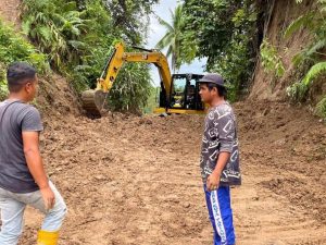 Alat berat membersihkan material longsor yang menimbun badan jalan di Kabupaten Padang Pariaman.