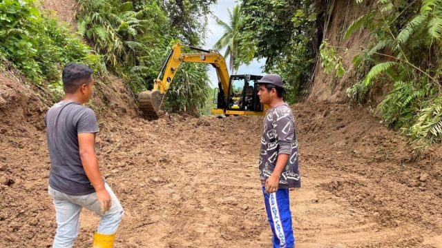 Alat berat membersihkan material longsor yang menimbun badan jalan di Kabupaten Padang Pariaman.
