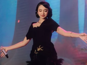 Lyodra Ginting bergaun hitam merentangkan tangan di atas panggung