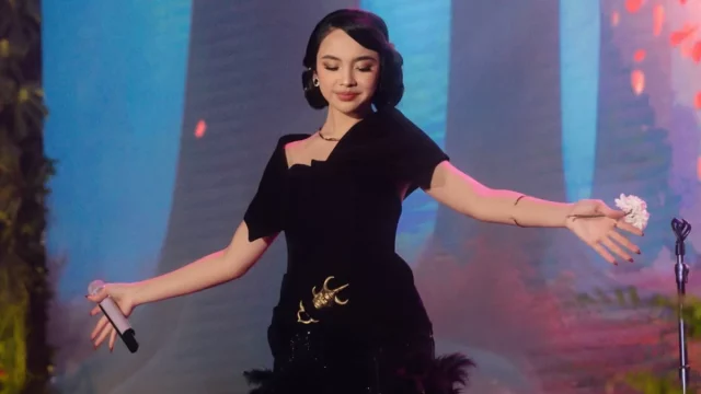 Lyodra Ginting bergaun hitam merentangkan tangan di atas panggung