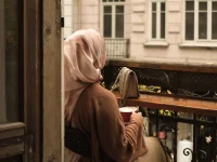 Seorang perempuan menikmati waktu sendiri di balkon sambil memandang kota.