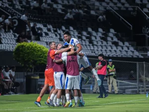 Sekelompok pemain sepak bola berpelukan merayakan gol di tepi lapangan sebuah stadion