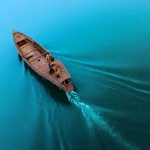 Perahu kayu melaju sendirian di perairan luas