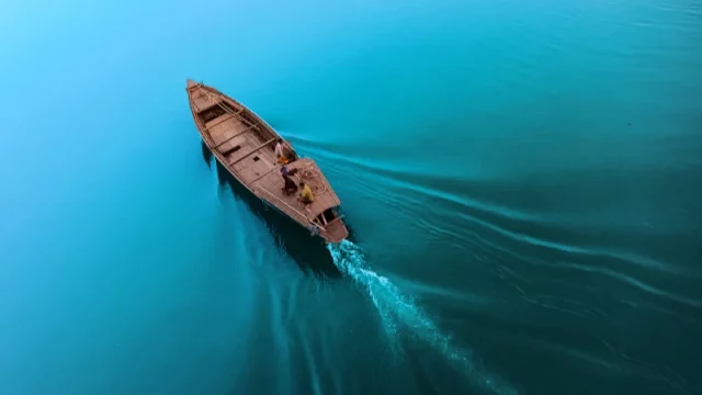 Perahu kayu melaju sendirian di perairan luas