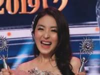 Natasha Wilona tertawa sambil mengangkat dua piala penghargaan di atas panggung