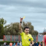 Wasit mengangkat kartu kuning dalam sebuah pertandingan