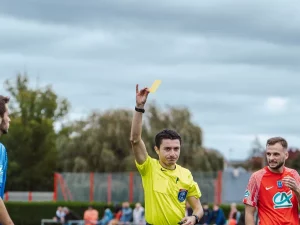 Wasit mengangkat kartu kuning dalam sebuah pertandingan