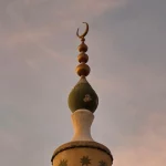 Puncak menara masjid berhias bulan sabit menjulang dengan latar langit jingga di Omdurman, Sudan
