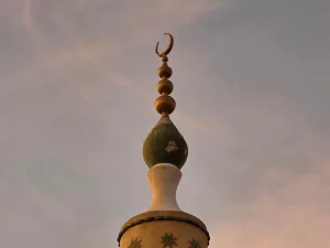 Puncak menara masjid berhias bulan sabit menjulang dengan latar langit jingga di Omdurman, Sudan