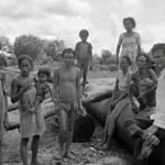 Sekelompok orang Sakai berdiri di sekitar pipa minyak Caltex di Kota Duri pada 1973