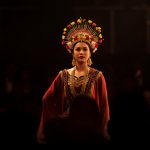 Ilustrasi penari berkostum tradisional bermahkota bunga di panggung terbuka malam hari