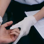 Dokter bersarung tangan memeriksa sendi tangan pasien