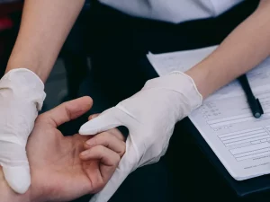 Dokter bersarung tangan memeriksa sendi tangan pasien