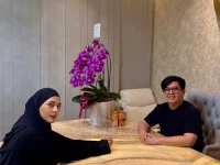 Paula Verhoeven berjilbab hitam duduk di meja bersama seorang tenaga medis