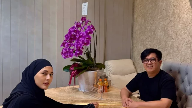 Paula Verhoeven berjilbab hitam duduk di meja bersama seorang tenaga medis