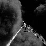 Petugas pemadam kebakaran menyemprotkan air ke kepulan asap