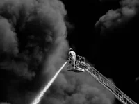 Petugas pemadam kebakaran menyemprotkan air ke kepulan asap