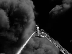 Petugas pemadam kebakaran menyemprotkan air ke kepulan asap