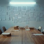 Ilustrasi meja kayu panjang di ruang diskusi dengan gelas kopi dan tumpukan buku