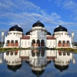 Masjid Raya Baiturrahman di Banda Aceh dengan kubah hitam dan bayangannya di kolam pantul
