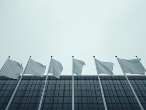 Ilustrasi deretan tiang bendera negara-negara Eropa di depan gedung kaca pemerintahan.