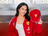 Pevita Pearce mengenakan jaket merah Scuderia Ferrari sambil memegang topi bertanda tangan di fasilitas Shell Helix, Italia