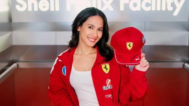 Pevita Pearce mengenakan jaket merah Scuderia Ferrari sambil memegang topi bertanda tangan di fasilitas Shell Helix, Italia