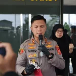 Kapolres Garut berseragam cokelat berbicara di depan mikrofon sambil menunjukkan barang bukti senjata pukul