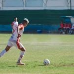 Pesepak bola menggiring bola di lapangan