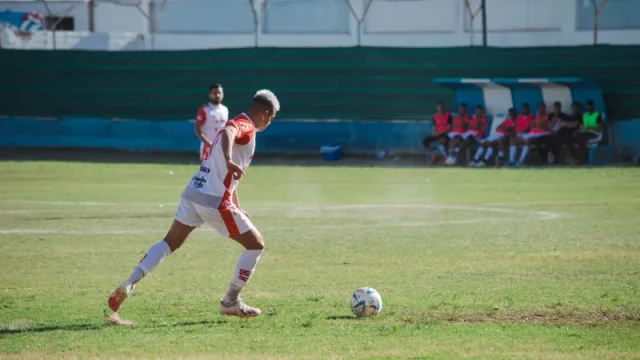 Pesepak bola menggiring bola di lapangan