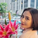 Prilly Latuconsina menoleh ke kamera sambil membawa bunga lili