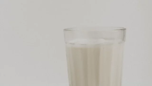 Segelas susu sapi segar di atas kain putih