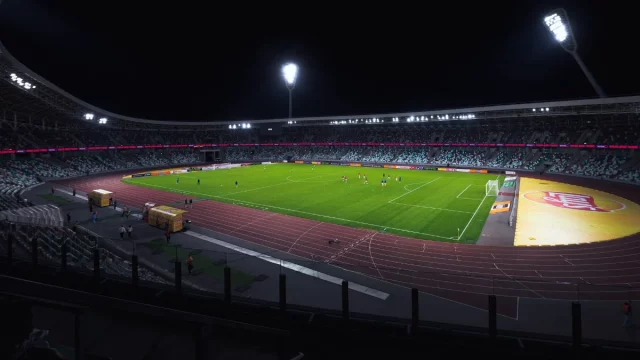 Ilustrasi stadion sepak bola dengan lampu menyala pada malam hari.