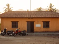 Bangunan puskesmas satu lantai berdinding polos di kawasan perdesaan dengan beberapa sepeda motor terparkir di halamannya