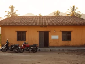 Bangunan puskesmas satu lantai berdinding polos di kawasan perdesaan dengan beberapa sepeda motor terparkir di halamannya