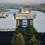 Bangunan pengendali pintu air di Sungai Danube dengan menara kuning dan aliran sungai yang tenang