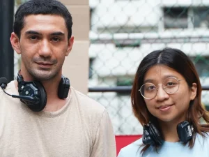 Reza Rahadian dan Sam Manacsa berpose bersama mengenakan headphone produksi di lokasi syuting